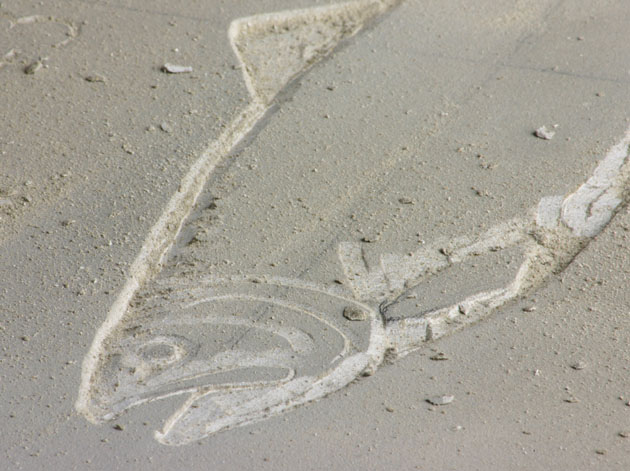 Carving a fish in relief on stone